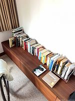 Wide view of entire lot on wooden cabinet showing full complement of books and metal rack