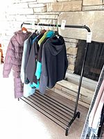 Full view of black metal garment rack loaded with sample clothing (not included)