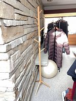 Full view of wooden coat rack against stone wall
