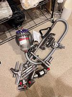 Full set showing canister body, hose, wand and various nozzle attachments scattered on floor