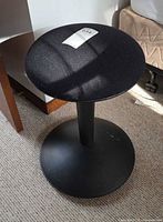 Full view of stool showing black fabric seat and circular base