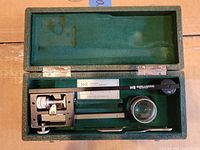 Planimeter and accessories in open green felt-lined case
