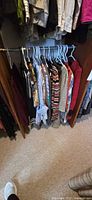 Closet rod with multiple striped, patterned and solid sweaters and tops on hangers