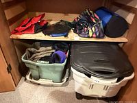 Shelf area containing multicolor duffel, blue sleeping bag sack, red nylon item, green tote and white bin