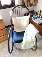 Full view of tubular metal rocking chair with cushion and blanket