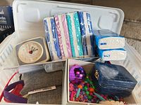 Plastic bin with alarm clock, tissue packs, binocular case, beads, ornament, jewelry box
