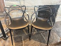 Front view of both matte black molded plastic armchairs