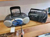 RCA and Sony boomboxes side by side on wood shelf
