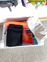Overview of clear bin containing scarves, tote and shoe bags