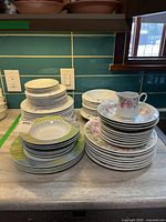 Three primary stacks of plates, bowls and saucers showing assorted patterns