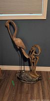 All three wooden sculptures standing together: tall bird, stylized bird, fish