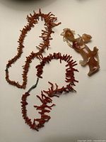 Both coral necklaces and Lotus Maiden carving laid out together