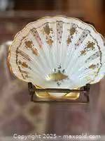 Front view of white porcelain clam shell dish with gold detailing