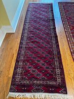 Full view of entire red Persian runner rug on hardwood floor