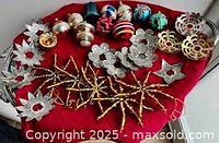 Group shot showing glass ornaments, foil stars, rosettes and bead snowflakes on red cloth