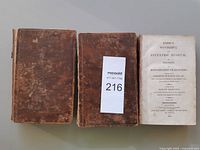Three leather volumes side by side, detached or missing boards visible with title page of 1803