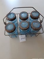 Six jars in wire caddy, side view