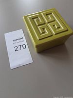 Square light green ceramic bowl with lid next to lot tag