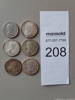 Obverse of six Canadian 50-cent coins alongside lot tag