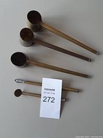 Three brass ibriki and two stirrers laid out