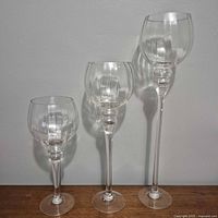 Three clear glass pillar candle holders standing side by side showing relative heights