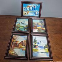 Group shot of five framed oil paintings on tabletop