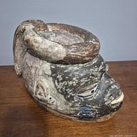 Front oblique view of carved wooden mask showing facial features and top crest