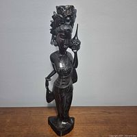 Front view of carved cocobolo wood Balinese goddess statue