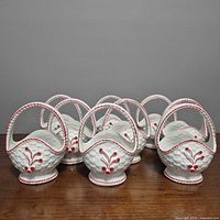 Group shot of nine white ceramic baskets with red accents
