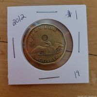 Reverse of 2012 Canadian Lucky Loonie in flip showing loon and Olympic emblem