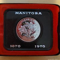 Reverse of 1970 Manitoba Centennial silver dollar in red-lined display holder
