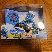 Front of sealed retail box showing Smurf on ATV and remote