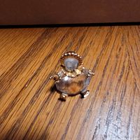 Front view of Swarovski crystal baby figurine showing faceted body, frosted head, gold-tone bonnet, arms and feet