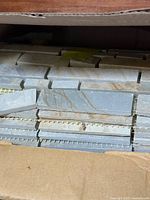 Stack of mesh-backed slate mosaic tiles inside carton