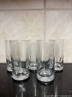 Five clear highball glasses in a row front view
