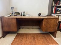 Front view of walnut desk showing patchwork top, pedestals, extra panel on floor