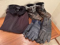 Group shot of boots, sweater, and two glove pairs