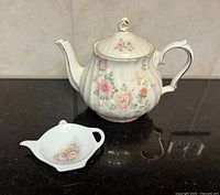 Front view of porcelain floral teapot and small dish