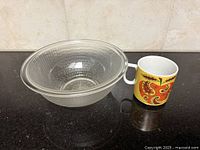 Pyrex clear glass bowl and ceramic paisley apple mug side by side