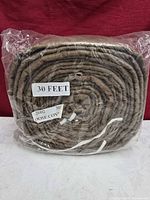 Front view of coiled padded hose cover in plastic, length label visible