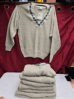 Sweater displayed on hanger and five folded identical pieces