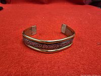 Front view of two-tone cuff bracelet showing embossed floral copper band bordered by sterling silver