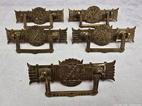 Front view of five brass Eastlake drawer pulls