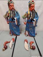 two ceramic Guan Yu figurines side by side with detached parts displayed