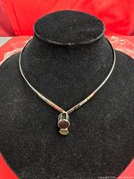 Front view of one silver-tone collar choker with cylindrical pendant and cabochon ends