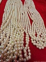 Multiple bundles of cream imitation pearl strands displayed on red background