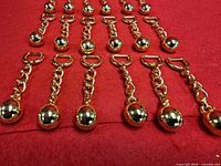 Twenty-four brass keychains laid out on red fabric