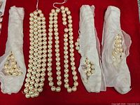 Six faux pearl necklace strands with protective tissue wrapping