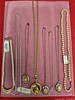 All seven necklaces laid out on pink board