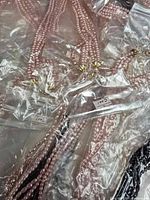 Multiple pink and black beaded necklaces in clear bags